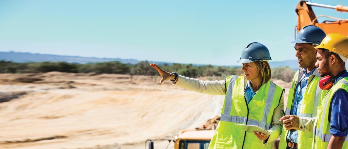 Image of three workers discussing construction plans outdoors.
