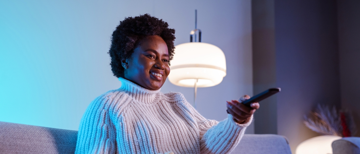 Woman sitting on a couch with popcorn watching television.