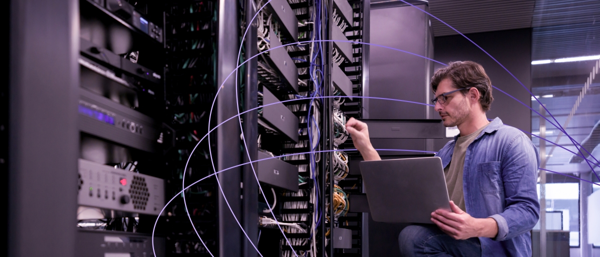 Image of a person using a laptop while working on network servers