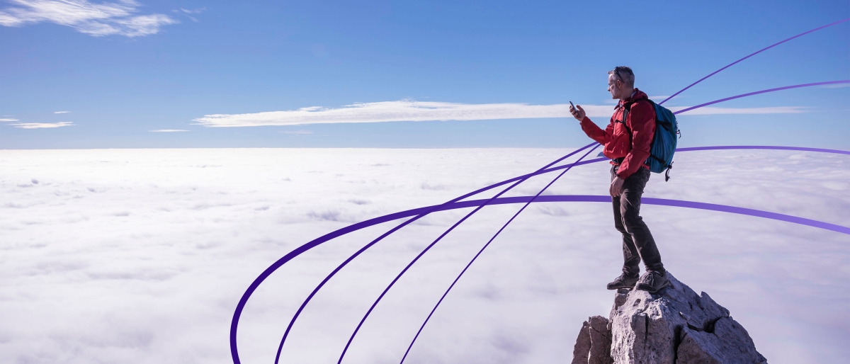 Image of a person using a phone on a rocky mountaintop.