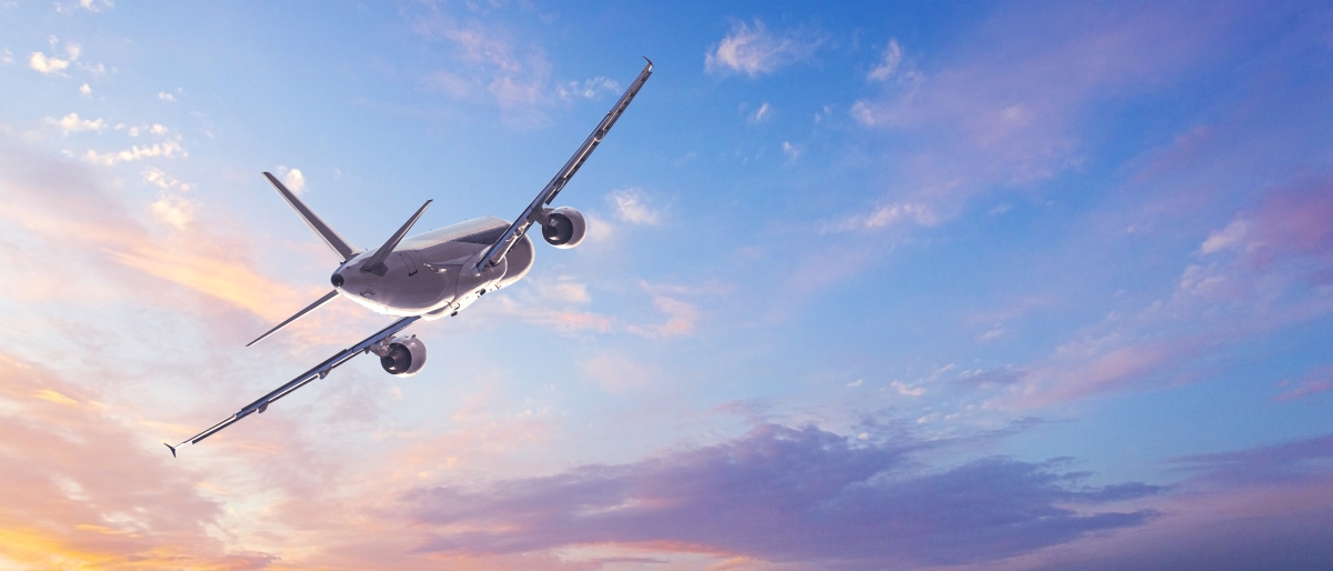 Image of an airplane with a sunset colours and clouds in the background