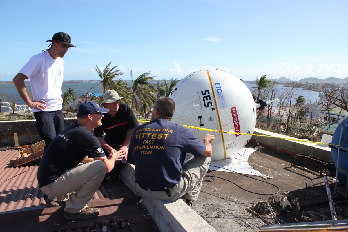 team of people discussing next to an inflatable satellite terminal on a roof