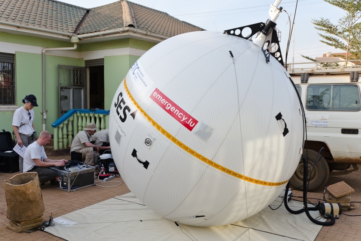 group of people working next to an inflatable satellite terminal