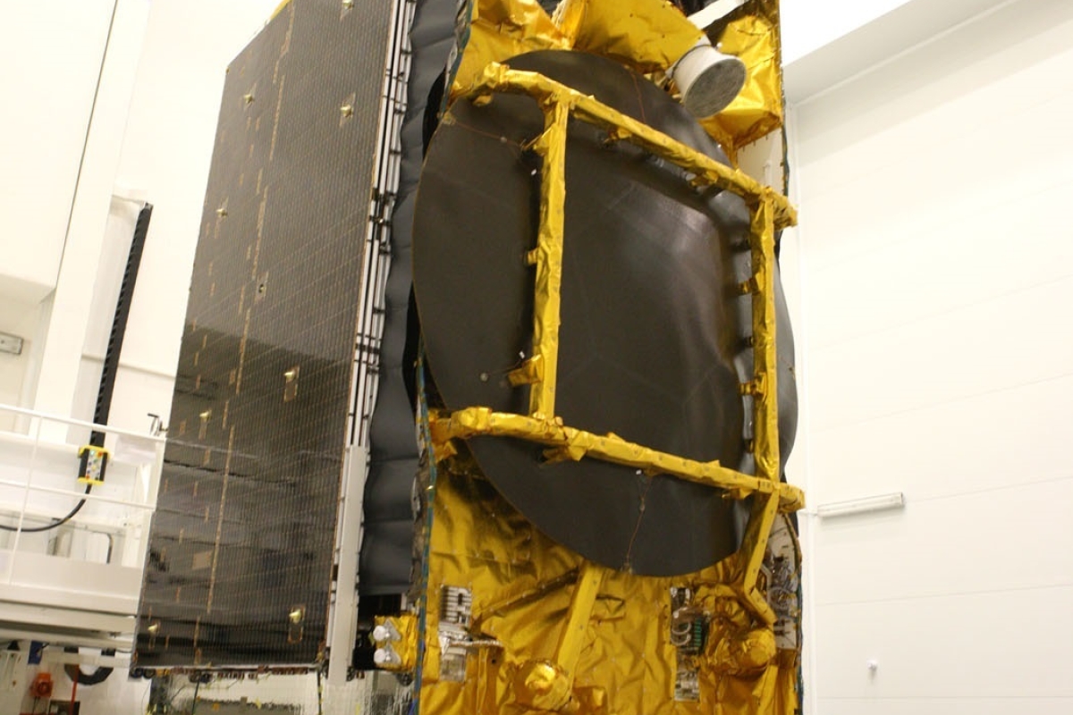 Technician working on a satellite bus covered with golden thermal blanket on supporting platform