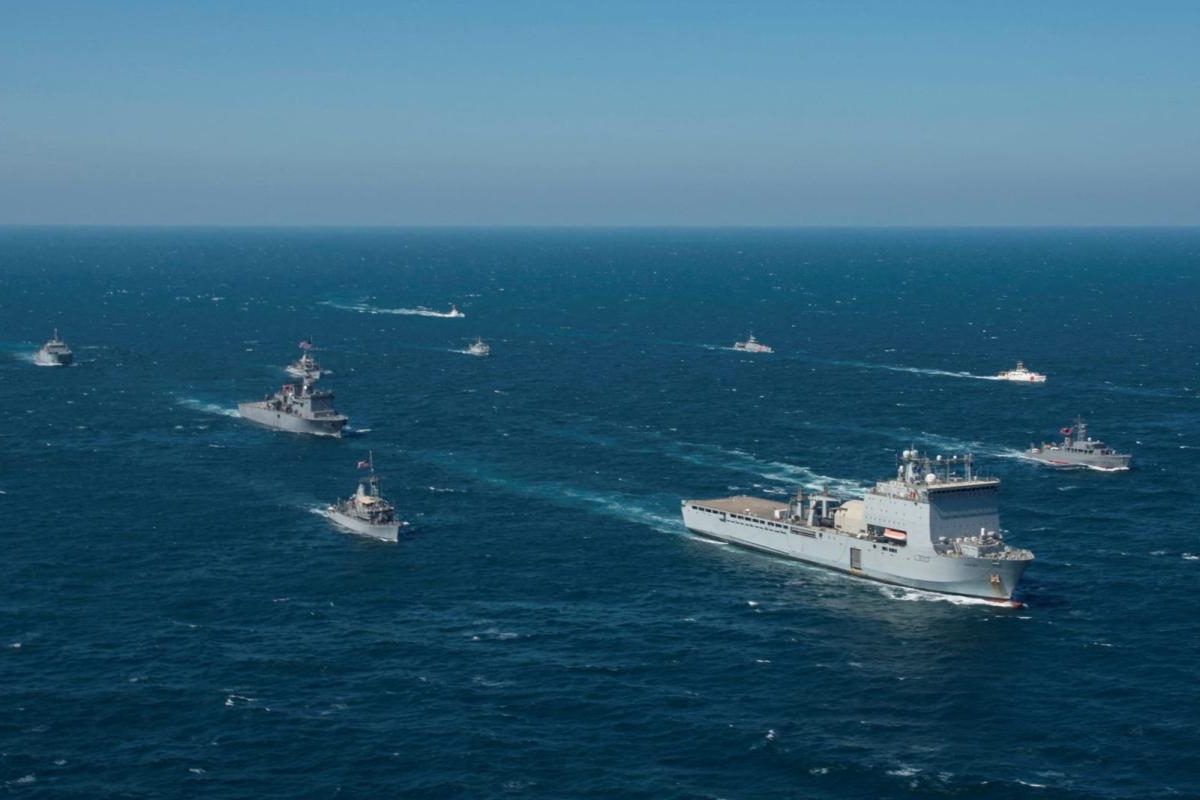 Image of naval vessels traveling in formation across open sea.