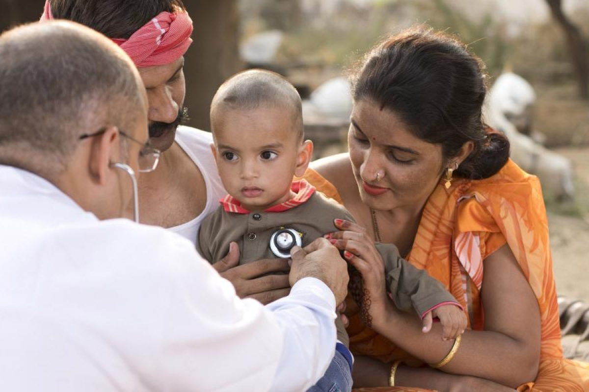Image of a doctor using a stethoscope to examine a baby held by family