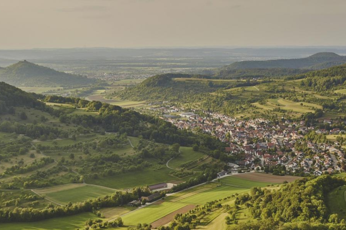 Green valley landscape with a small town nestled between rolling hills.