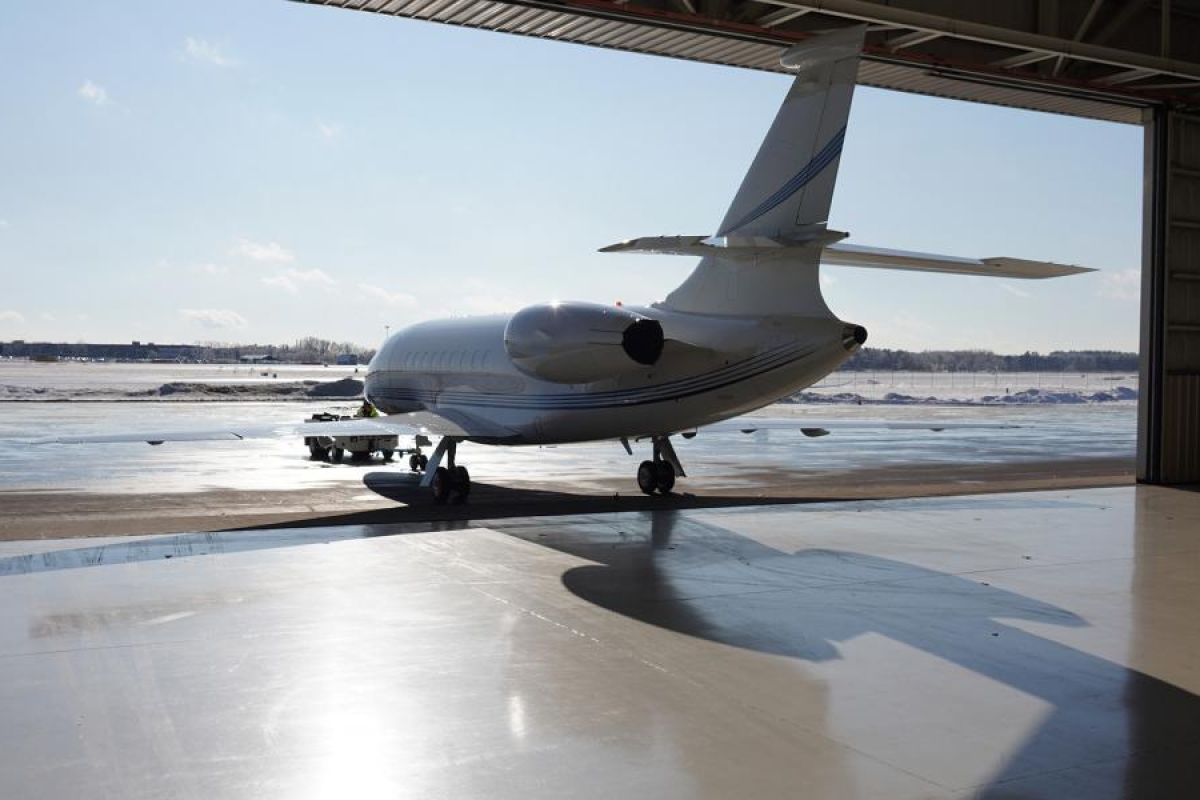 Image of a jet parked at the edge of an aircraft hangar