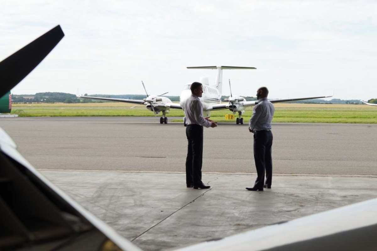 Image of two people standing near aircraft on an airport tarmac.