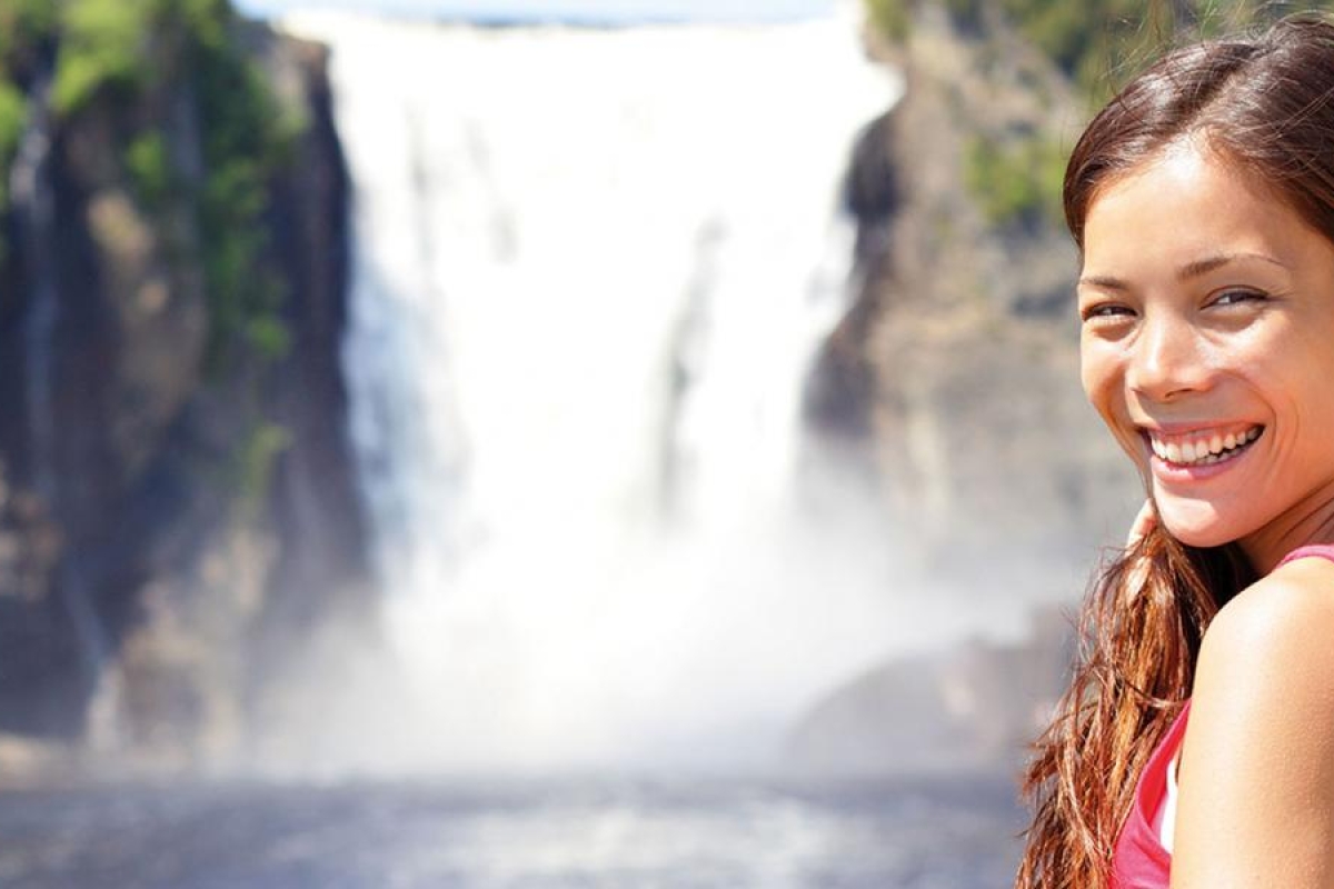 Image of a person standing by a large waterfall.