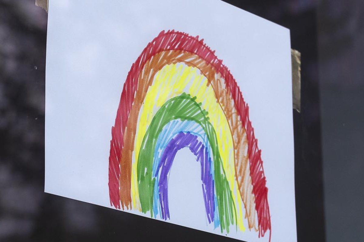 Image of a drawing of a rainbow taped to a window.