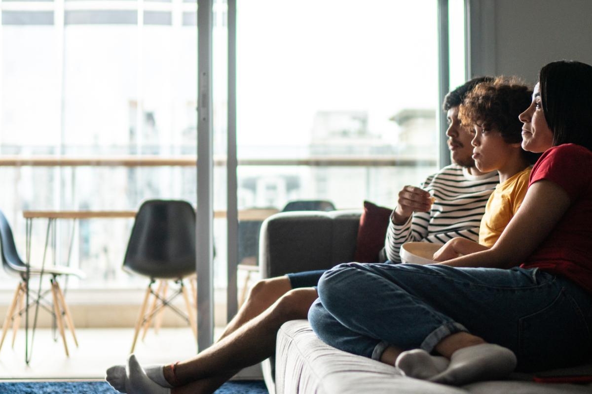 Image of an adult and two kids watching television in the living room.