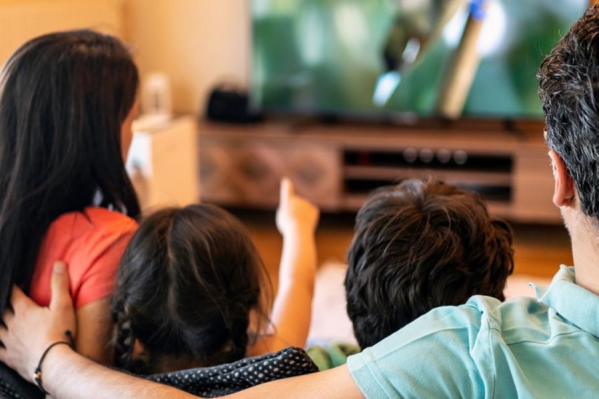 Image of a family sitting on the couch watching television.