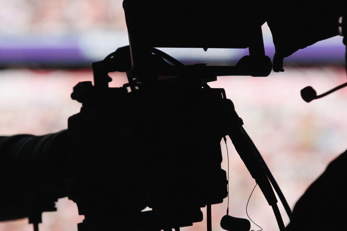 Image of silhouette of a camera operator filming with a broadcast camera.