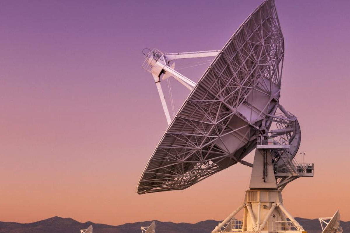 Image of a large satellite dish pointed skyward at sunset