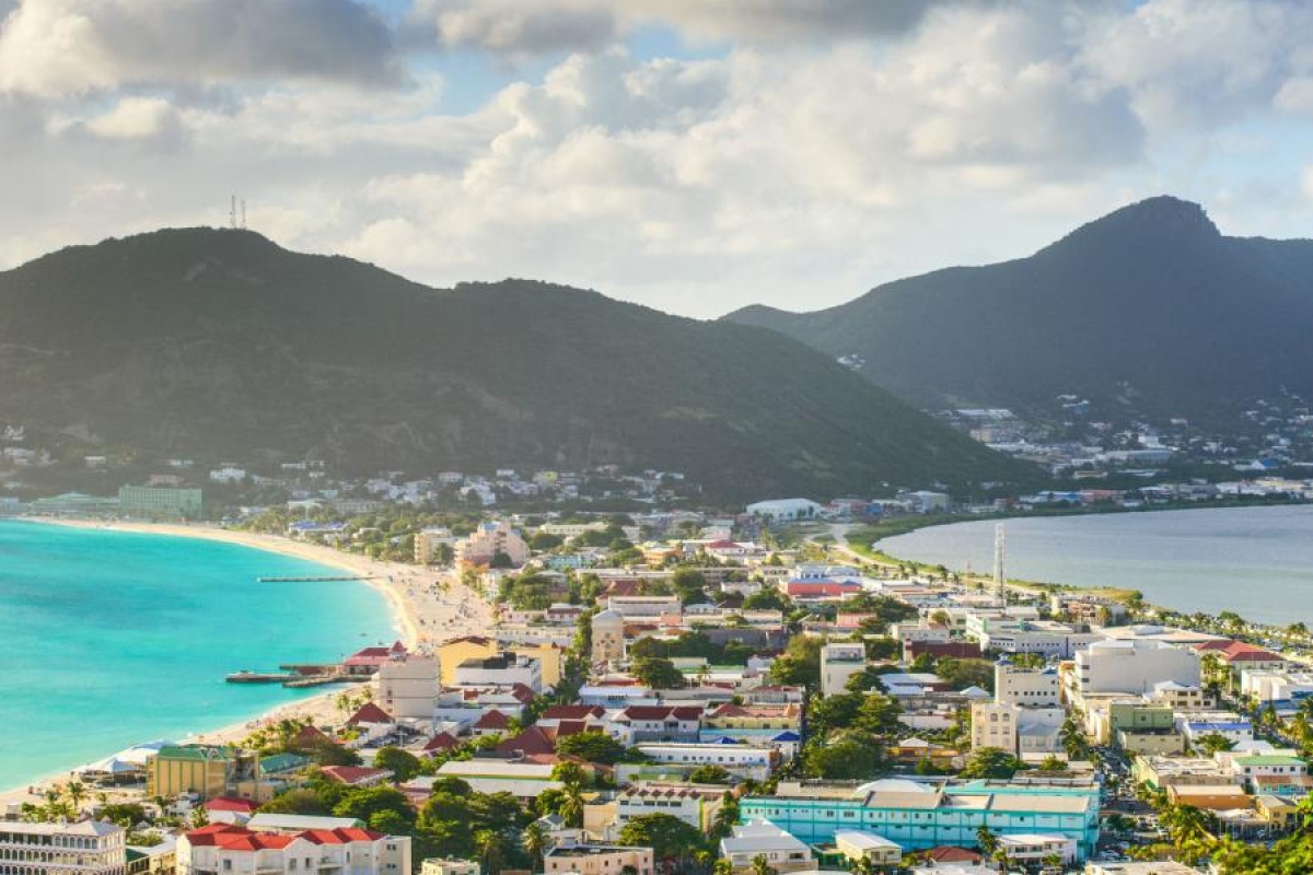 Landscape image of a coastal city with turquoise water, beaches, and mountains in the background