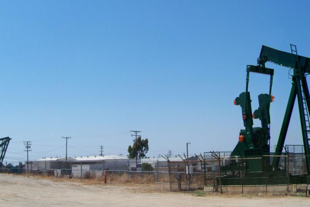 Image of oil pumpjacks operating in a fenced field.
