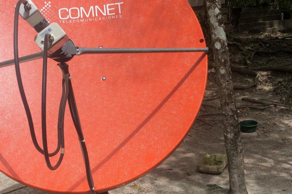 Image of a red COMNET satellite dish mounted outdoors.