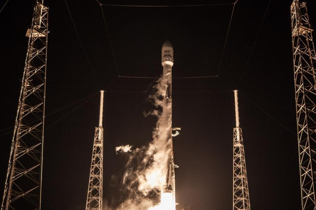 Image of a rocket launching at night from a pad surrounded by tall support towers.