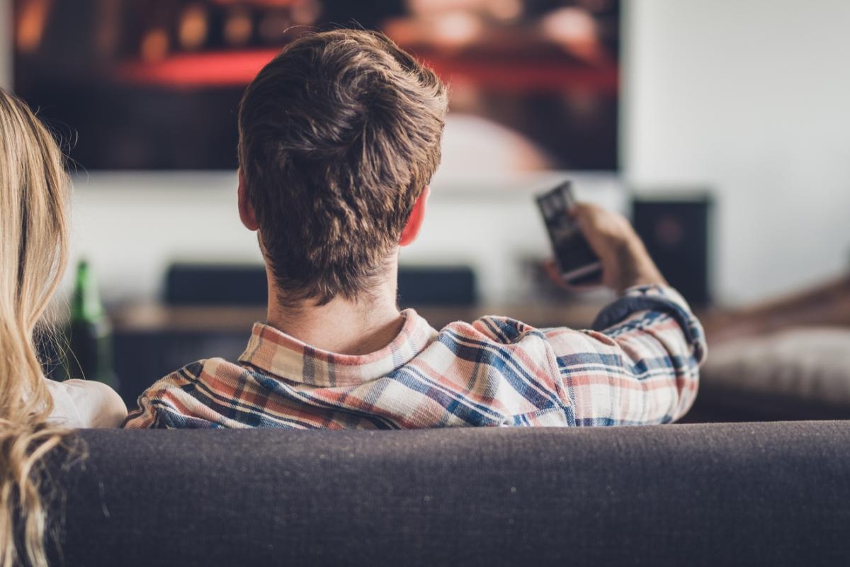 Image of two people on the couch watching television.