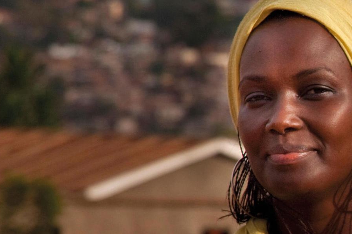 Image of a person wearing a yellow headscarf standing in a village setting.