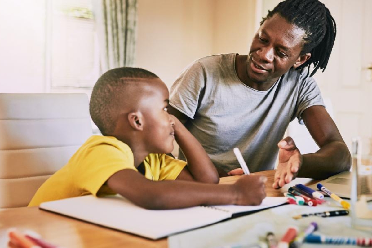 Image of an adult teaching a kid with a latptop.