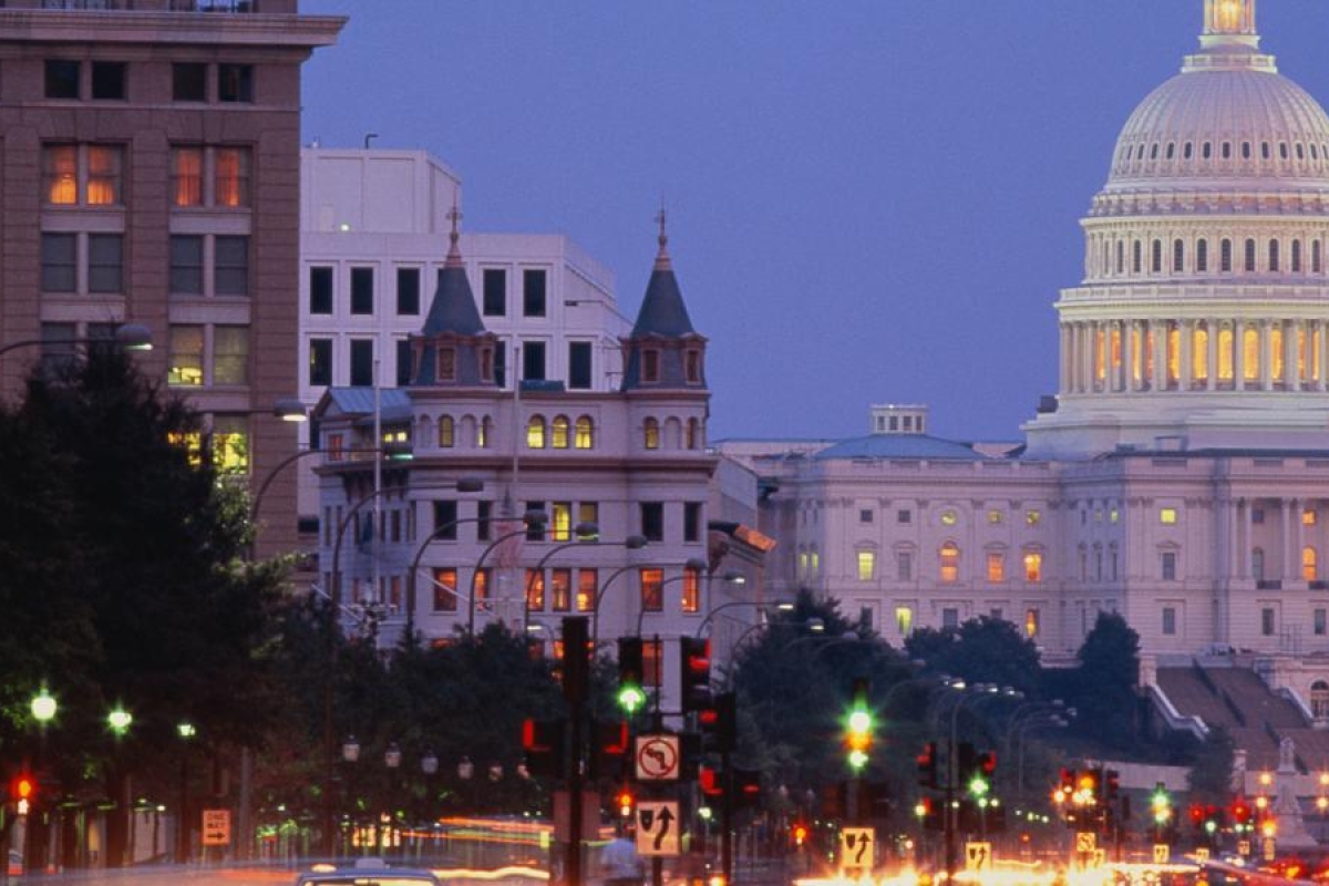 Image of a night view of a city street leading to a brightly lit building.