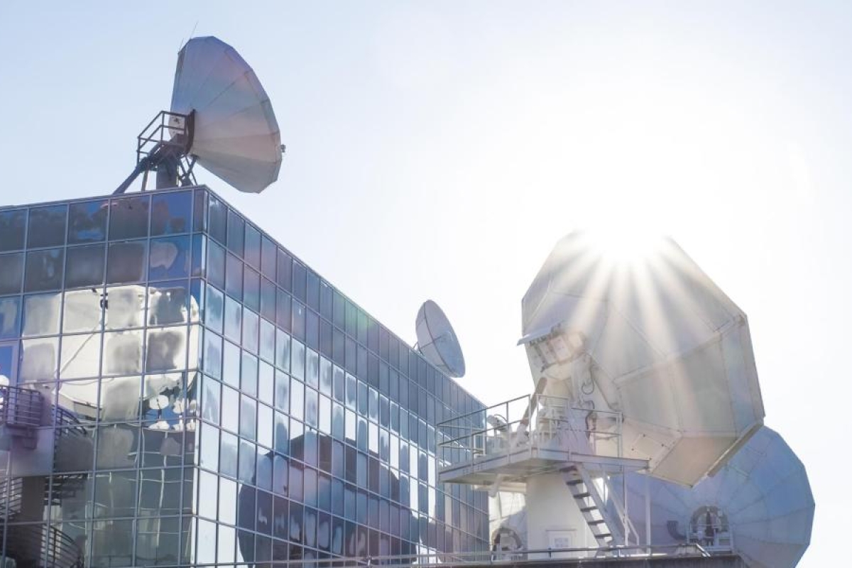 Glass building with large satellite dishes.