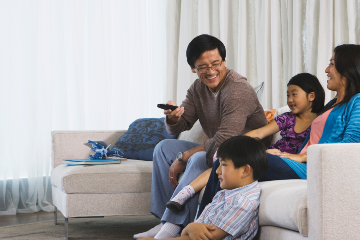 Image of a family chilling on the couch watching TV.