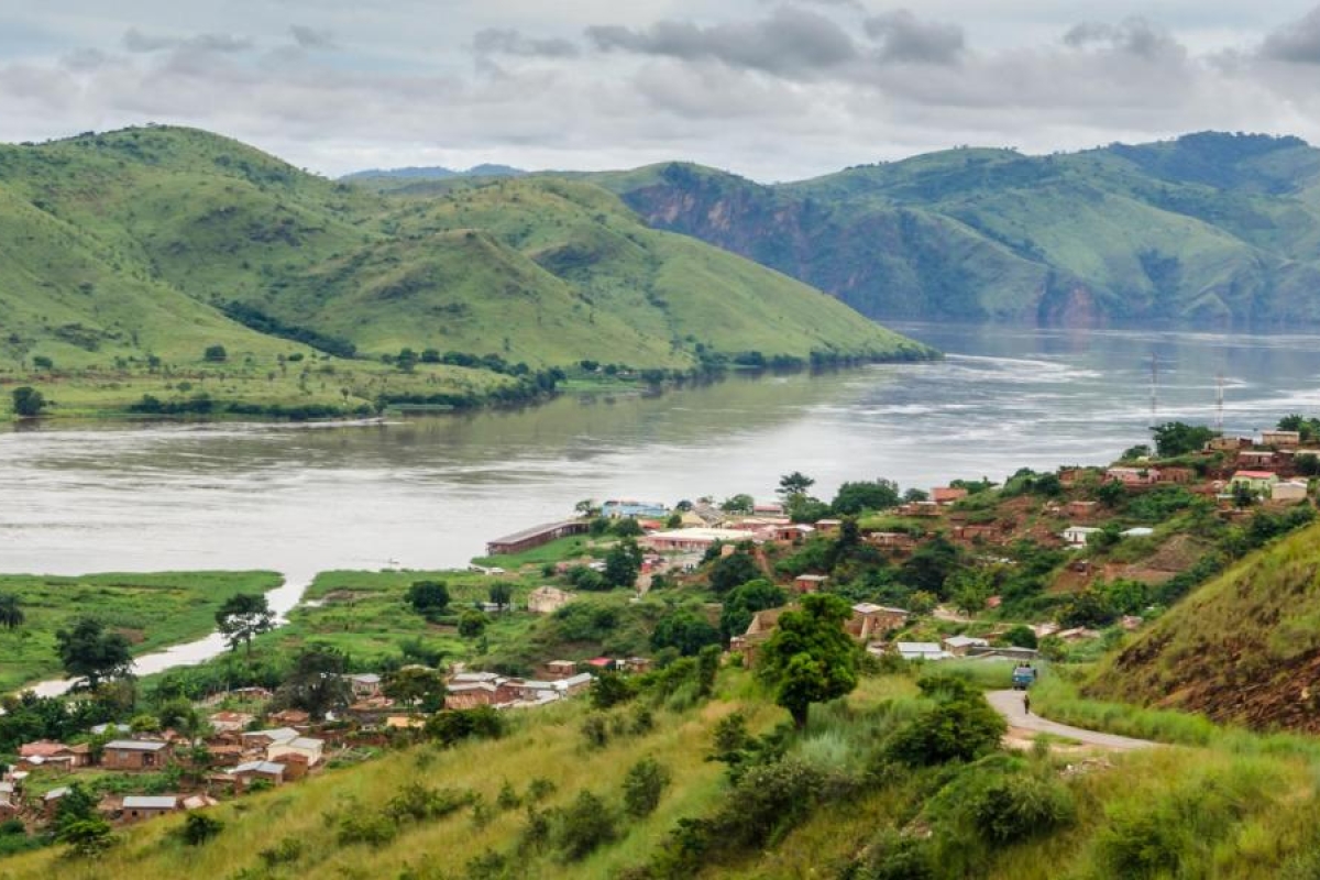 Landscape image of a riverside village with green hills and a wide river.