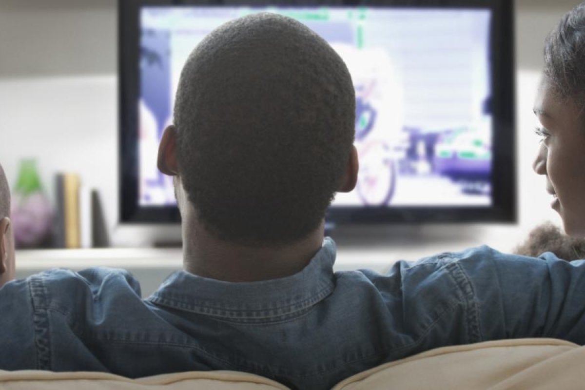 Image of a family sitting on a couch watching TV.