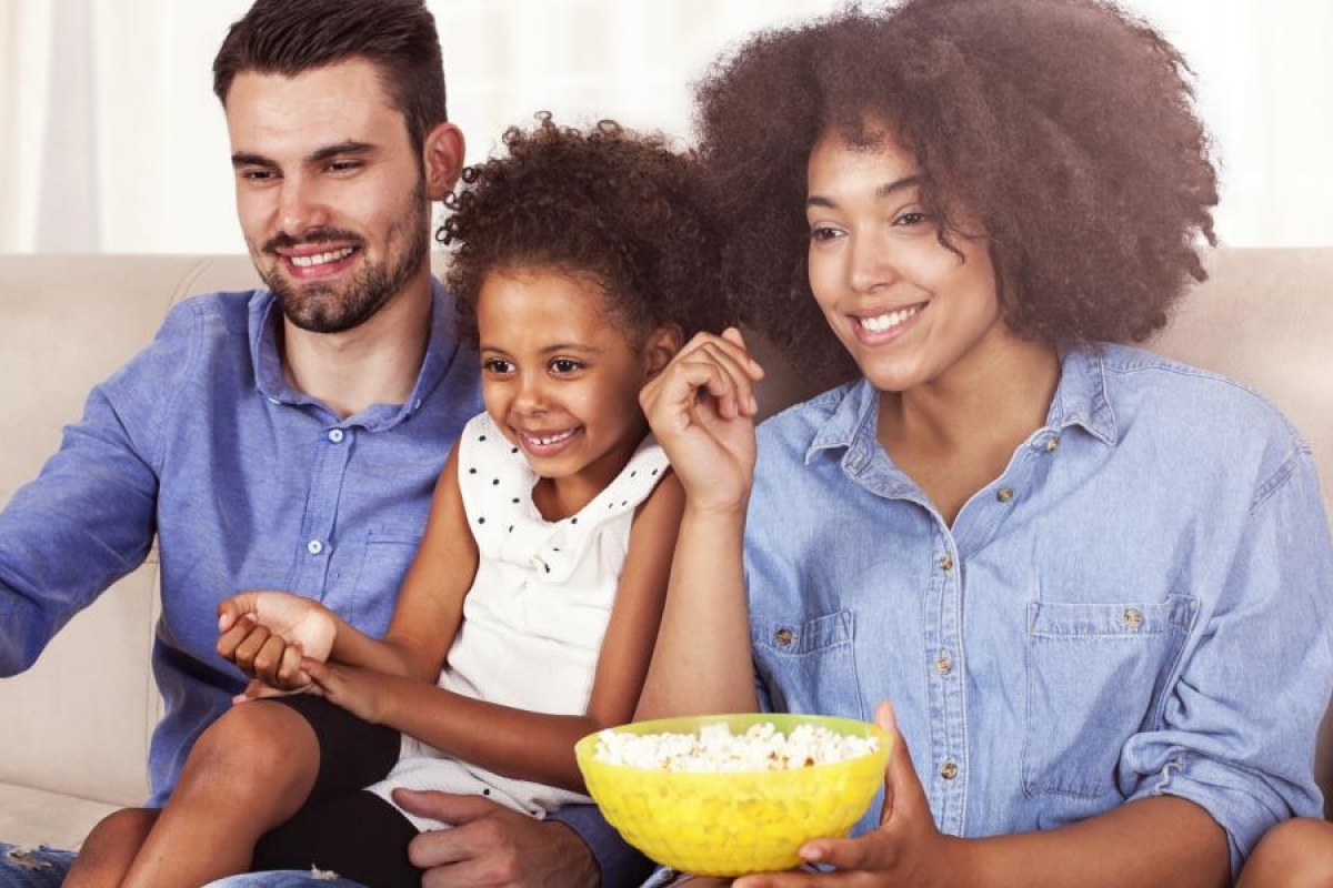 Image of a family sitting on a couch and enjoying watching television.