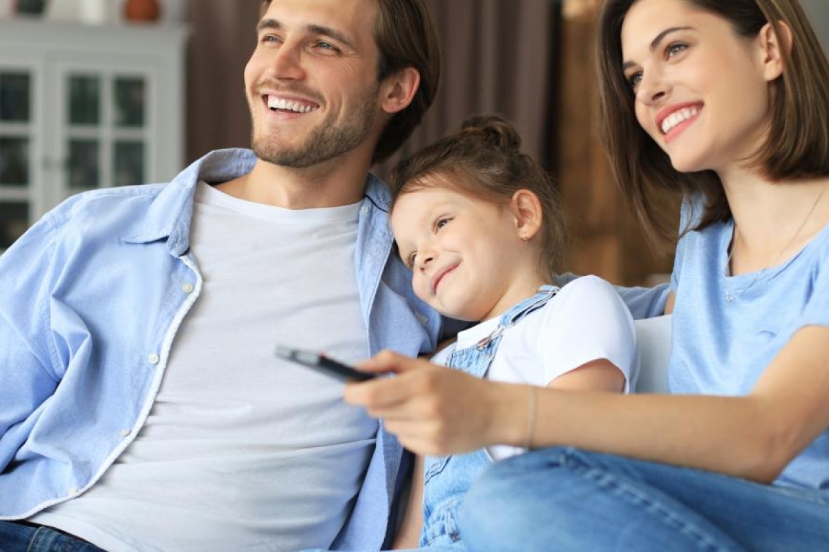Image of a family sitting on the couch watching television.