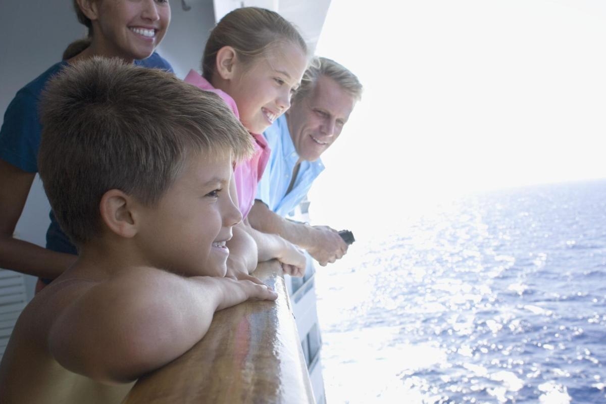 Image of kids and an adult enjoying the sea from a cruise ship.