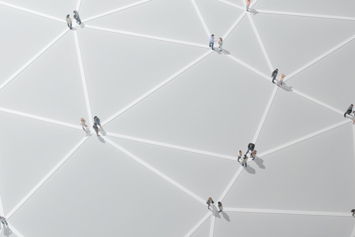 People walking across a geometric, network‑like patterned surface