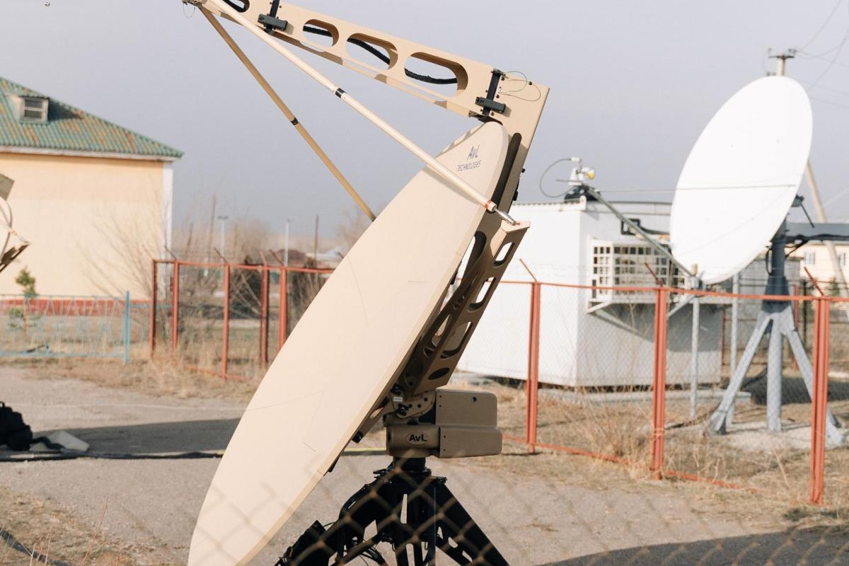 Portable tan satellite dishes set up outdoors near fixed white antennas