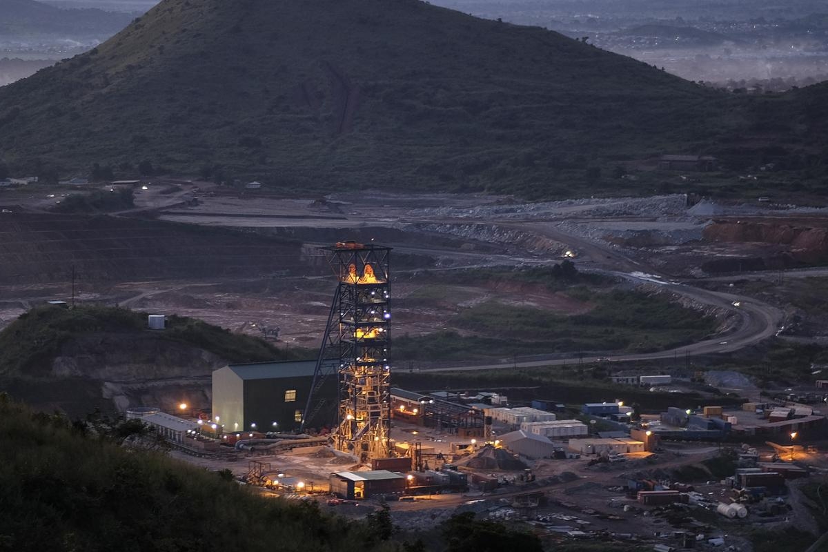 Image of illuminated mining site at dusk surrounded by hills.