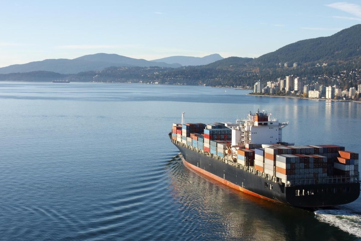 Image of a cargo ship sailing through a coastal bay toward the city.