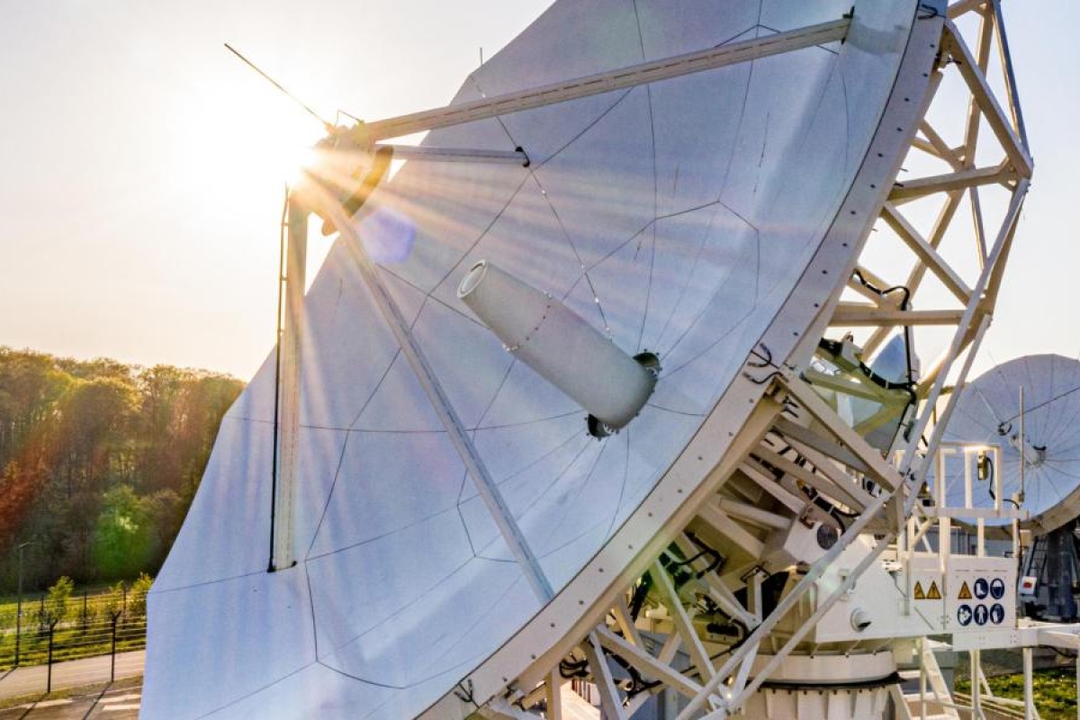 Image of a big antenna dish with sun rays coming through.