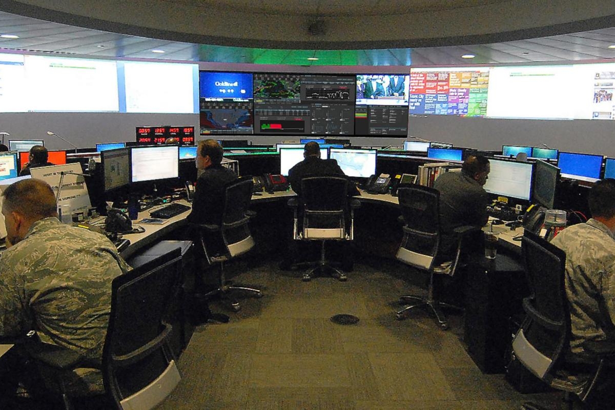 Image of military-style command center with personnel monitoring multiple screens.