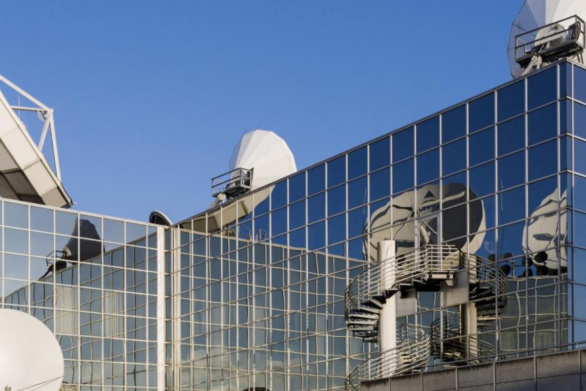 Image of antennas mounted on top of a glass building.