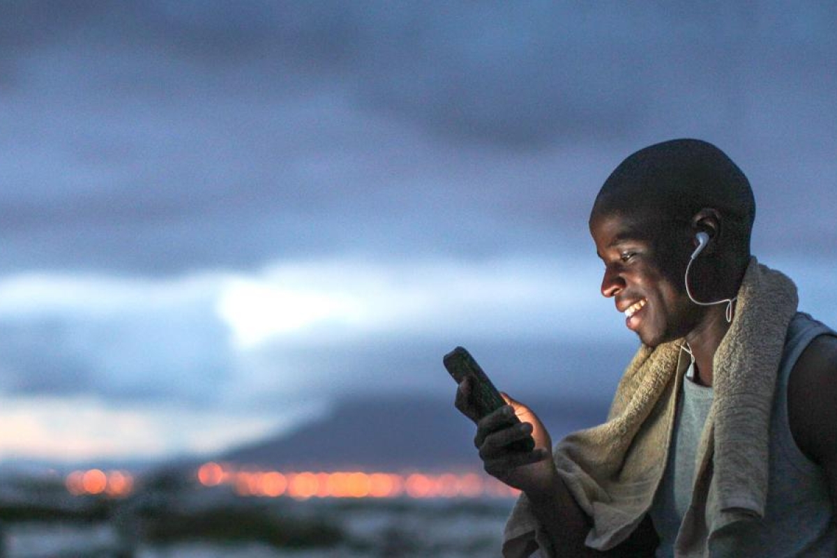 Image of a person using a mobile phone outdoors at dusk.