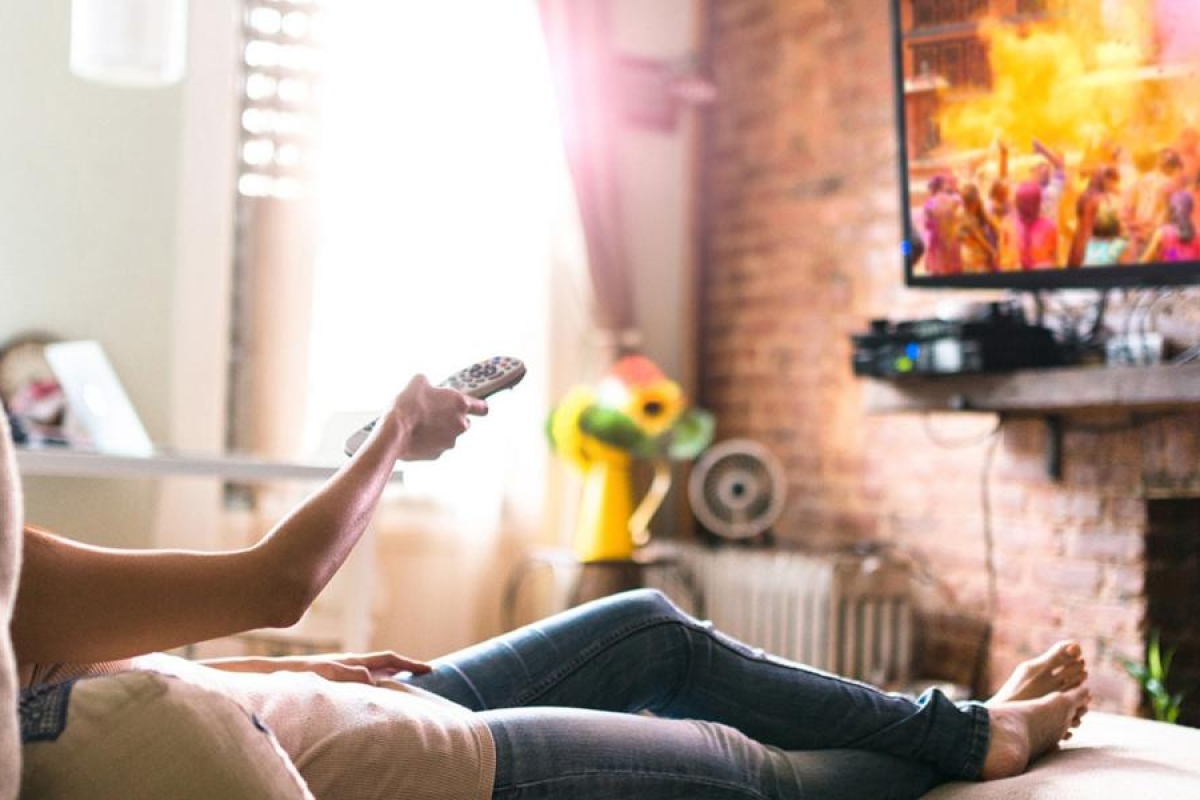Image of a person relaxing on the couch watching television.