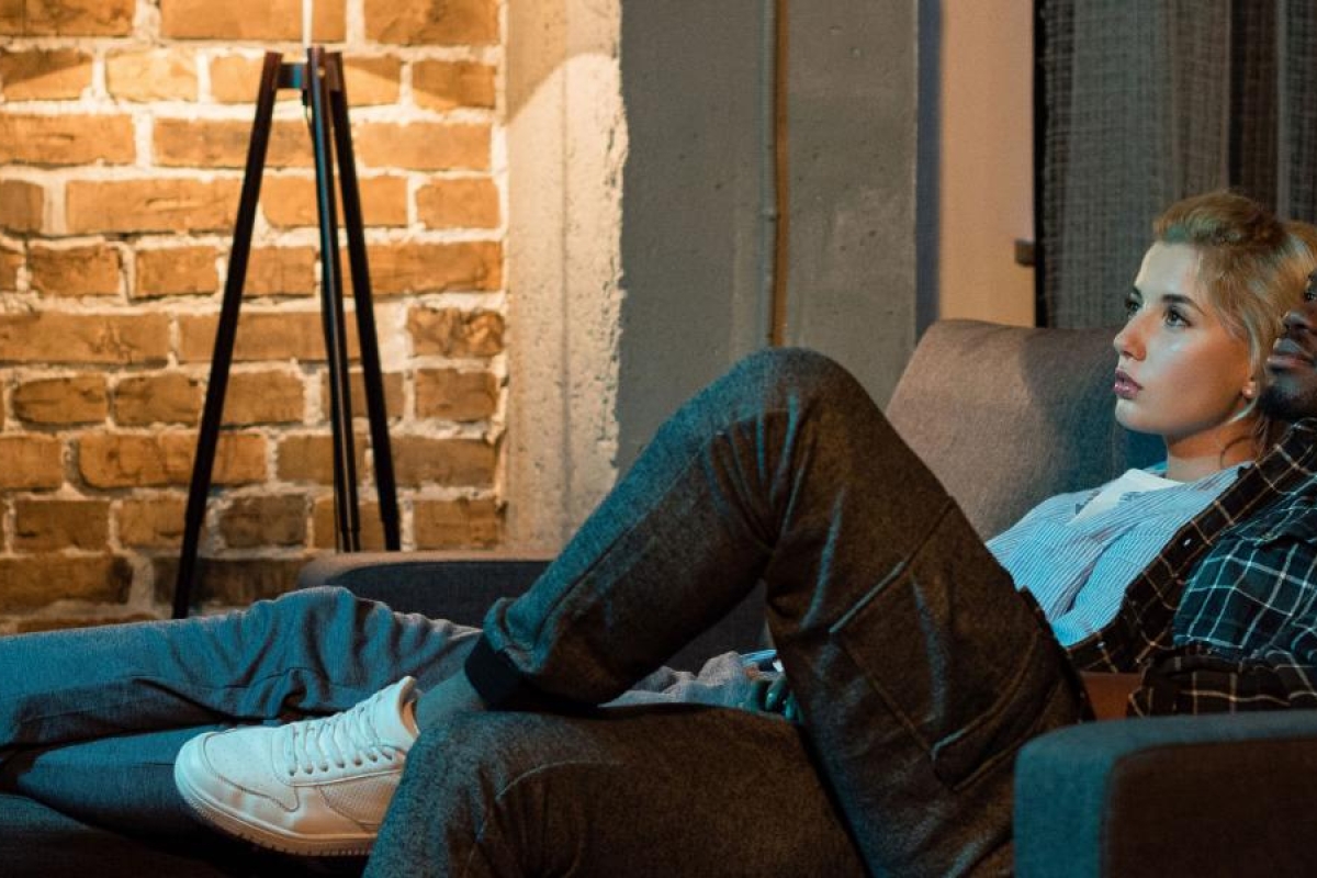 Two people on the couch watching television.