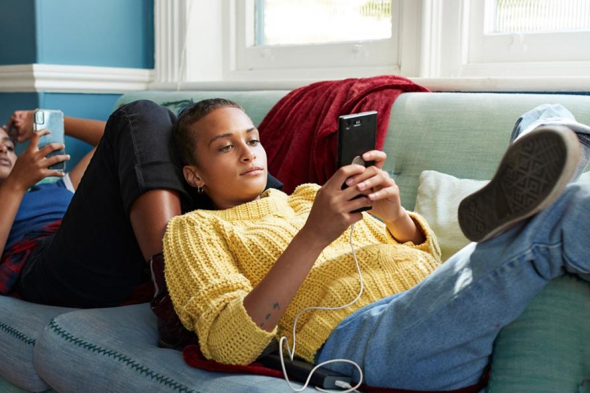 Two people relaxing on the couch using mobile phones.