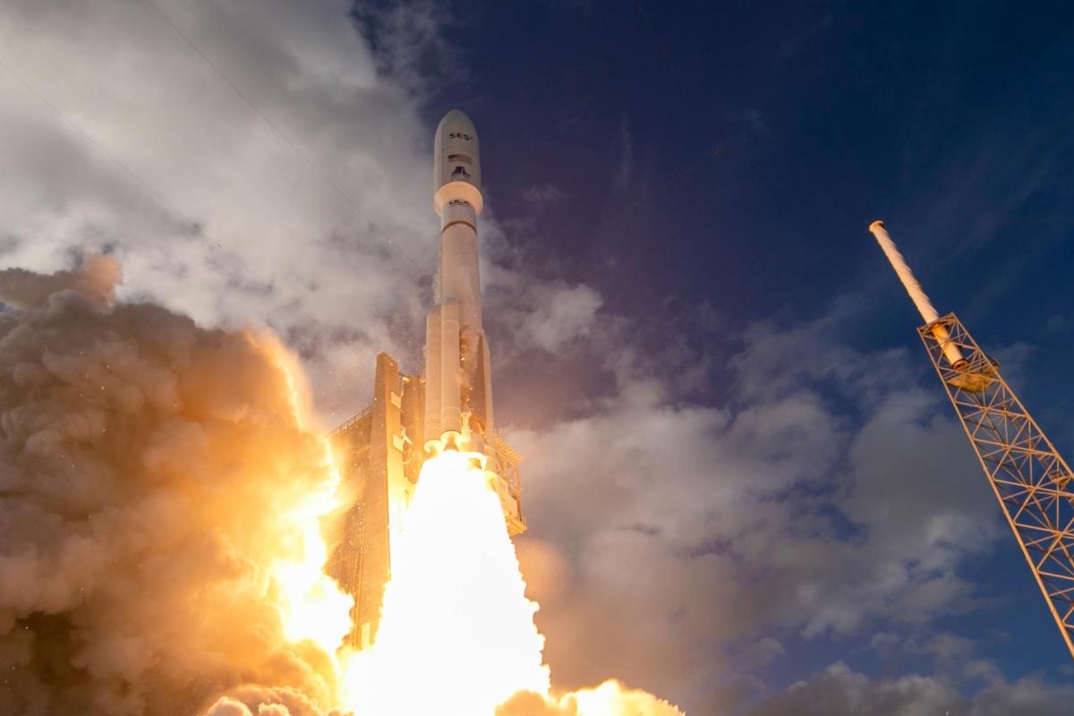 Image of rocket lifting off with bright exhaust flames against a cloudy sky.