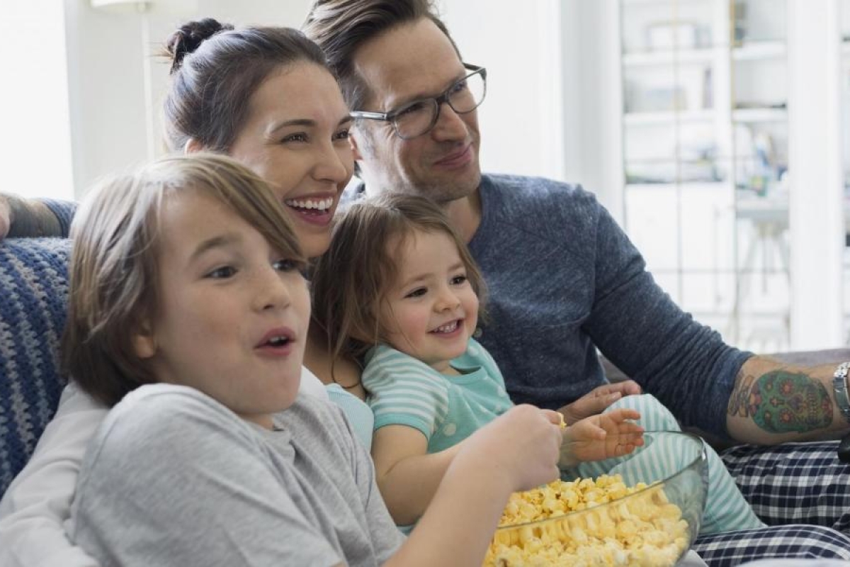 Image of a family sitting on the couch watching television.