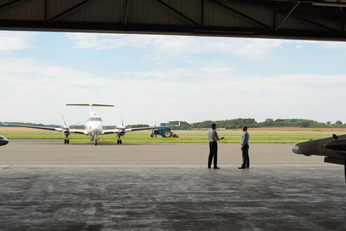 Image of a plane in an aerodrome and two people next to it.