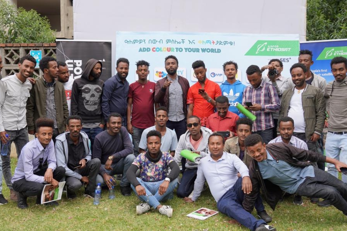 Image of a group of people posing together outdoors in front of event banners.