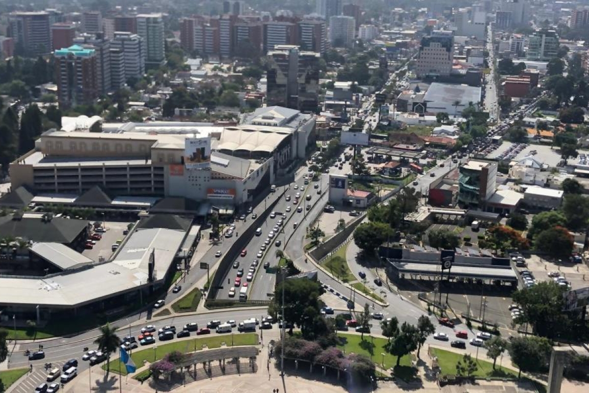 Image of cityscape with busy roads, buildings, and traffic viewed from above